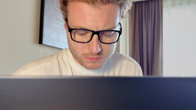 A young man works on a laptop from home