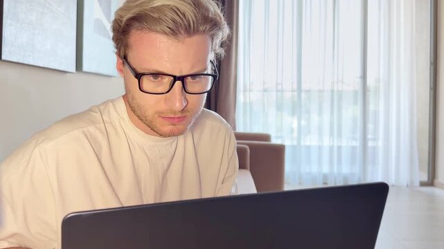A young man works on a laptop from home