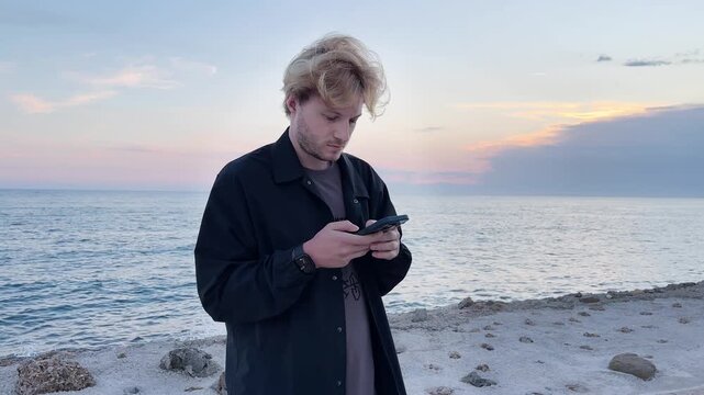 young man walking along the promenade and taking pictures.uses a smartphone