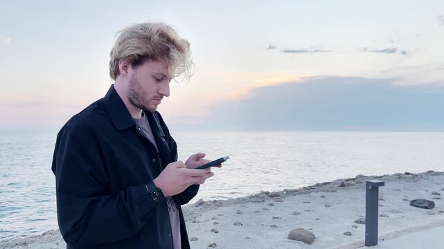 young man walking along the promenade and taking pictures.uses a smartphone
