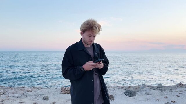 young man walking along the promenade and taking pictures.uses a smartphone