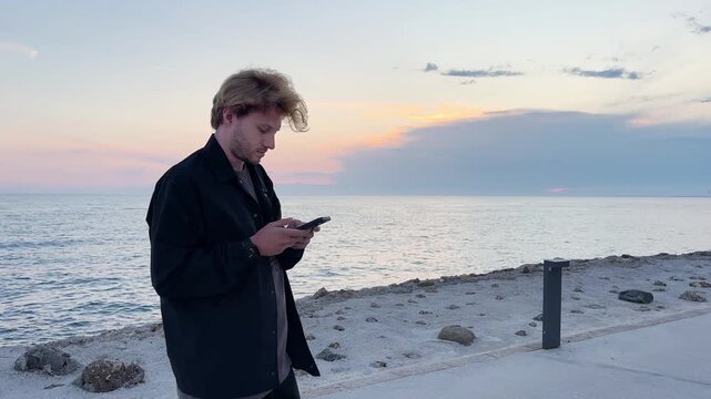 young man walking along the promenade and taking pictures.uses a smartphone