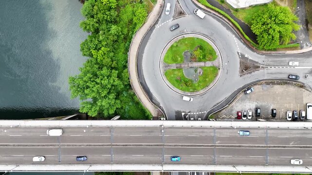 Aerial view of the Rua Ribeirino roundabout and a bridge with traffic over the Minho River surrounded by lush green trees in Ourense, Ourense, Spain.