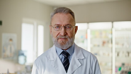 Fototapeta premium Senior pharmaceutical assistant posing drugs store portrait. Serious man doctor