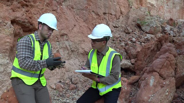 Two geologists analyzing soil and rock formations at a mining excavation site. They are conducting geological surveys and evaluating mineral resources for industrial project planning.