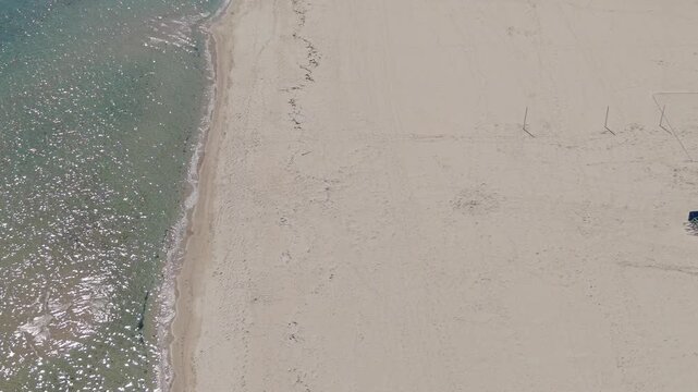 Aerial drone view capturing ocean shoreline textures with foamy surf and green sea waters nearby