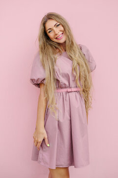 Smiling Woman In Pink Dress Against Pink Wall