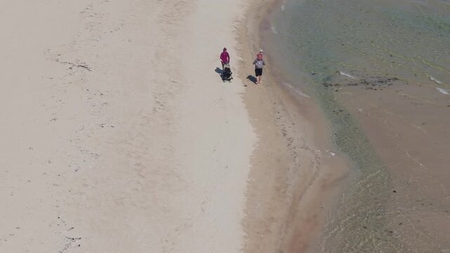 Top aerial perspective of turquoise ocean waves creating foam patterns beside sandy beach shoreline nearby