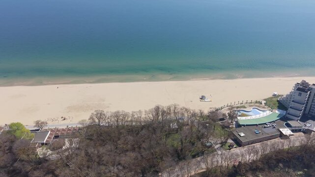Aerial drone view of ocean waves crashing onto sandy beach with turquoise coastal water nearby
