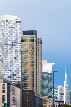 From a vertical street opening, Frankfurt Germany skyline towers align across the financial district with restrained urban architecture