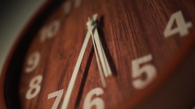 Close-up view of a wooden wall clock showing the time, with a focus on its detailed texture and the passage of time