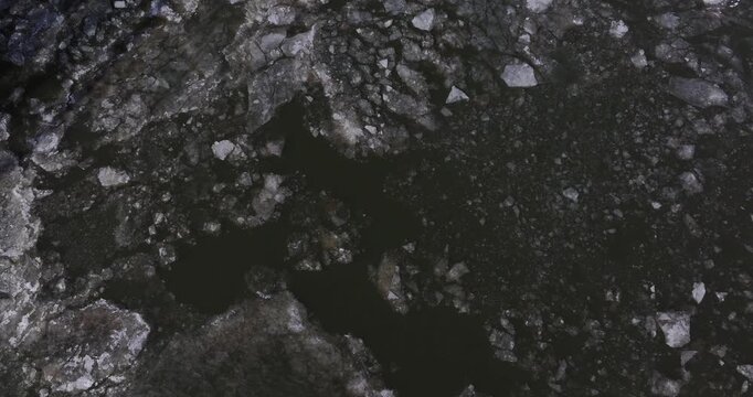 Aerial view of fragmented ice sheets and frozen chunks floating on the dark surface of a river during winter Cincinnati, Ohio, United States.
