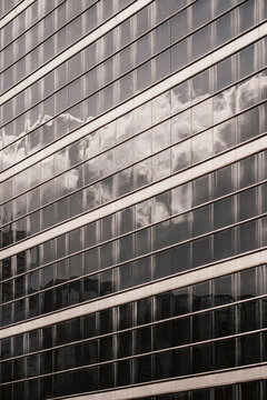 Horizontal windows stretch across a glass facade as reflections turn office buildings into abstract corporate architecture patterns
