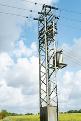 Obraz premium Electricity pylon with transformer standing in green field