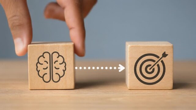 Concept of achieving goals with brainpower and strategy shown by wooden blocks with brain and target icons