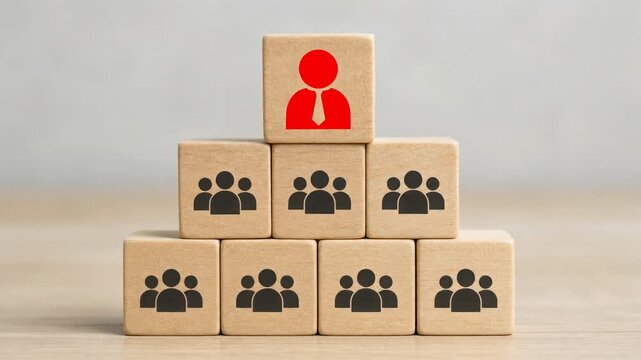 Wooden blocks stacked in pyramid shape showing leader icon in red above groups representing teamwork and management