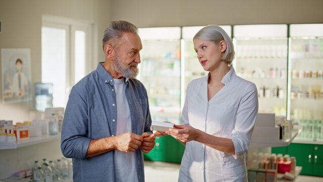 Pharmacist doctor help customer with medicine recommendation at pharmacy closeup
