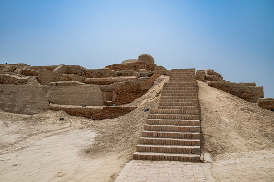 Visiting the ancient site of Moenjodaro shows the steps leading up to historic structures in a dry landscape in Pakistan