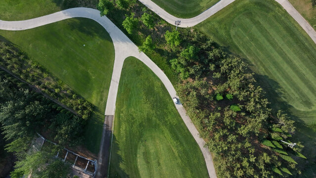 Aerial view of a golf course with winding pathways through lush green fairways and tree-lined areas