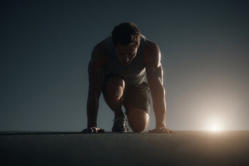 Obraz premium Athletic man in sportswear prepares to sprint at dawn, crouched in a starting position on an outdoor track. Focused runner readies himself for an intense early morning workout session