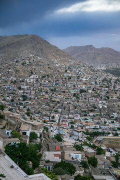 View of the city of Kabul from a high point showing buildings and mountains under a cloudy sky