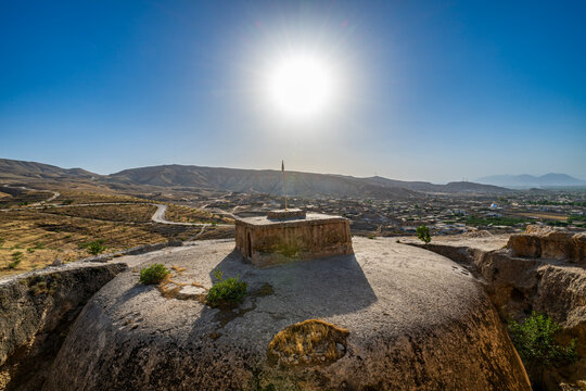 Giant stupa carved in rock stands in sunlight over landscape in Afghanistan