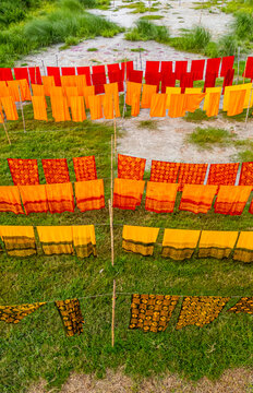 Freshly dyed clothes hang to dry in a village field in Bangladesh, showcasing vibrant colors and traditional local craftsmanship