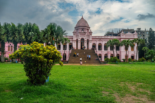 Visitors explore Pink Palace and gardens in Dhaka Bangladesh during a cloudy day in the late afternoon