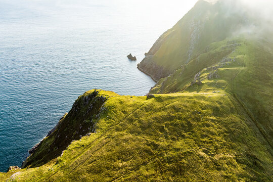 Moyteogue Head above Keem Bay on Achill Island, County Mayo, Ireland, glowing in evening sun. The steep cliff trail and dramatic Atlantic headland.