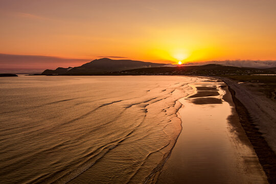 Aerial sunset view of Keem Beach on Achill Island, County Mayo, Ireland. Golden Atlantic light over the horseshoe bay, sand and cliffs of the Wild Atlantic Way.