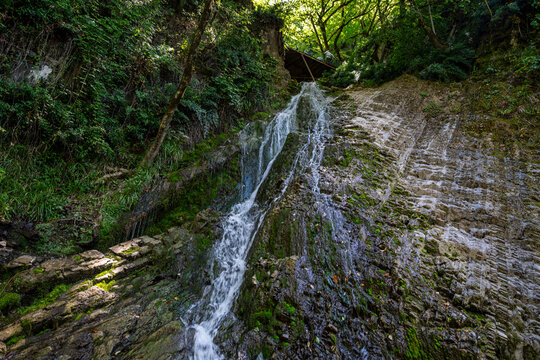 Waterfall flows over rocky surface surrounded by trees in Sheki, Azerbaijan during daytime in a natural setting