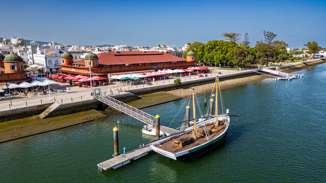 Sailing boat near market in Olhao, Algarve, Portugal with waterfront activity and local structures in view