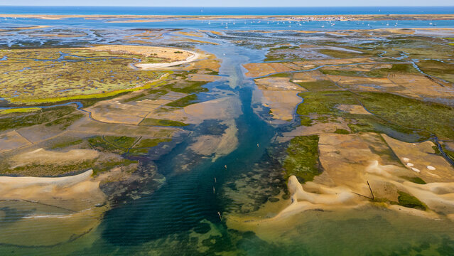 Aerial view of sandy wetlands showing waterways and patches of vegetation in Algarve region of Portugal
