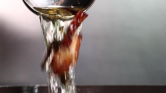 Oil from frying green onions and onions pouring out of ladle