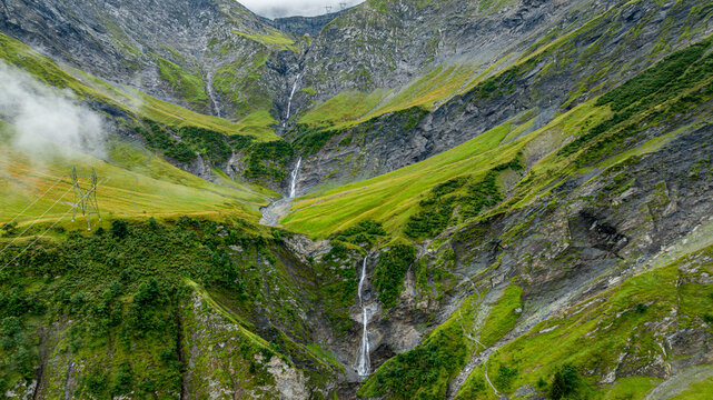 Waterfalls flow through Tschinglengorge in Sardona National Park in Switzerland with green mountains and rocky terrain
