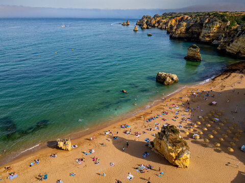Sunset views of beach cliffs by the sea in Algarve showing people enjoying time on the sand
