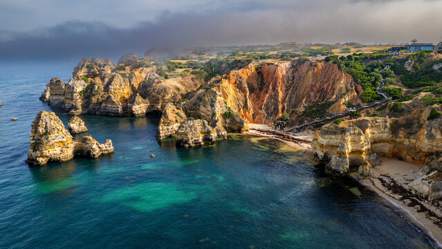 Beach cliffs surround the ocean with rocky formations at sunset in Algarve, Portugal near Lagos
