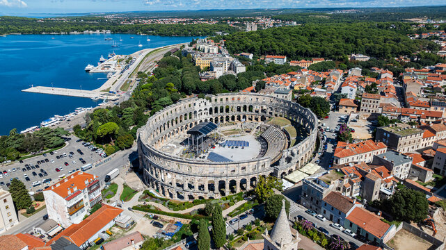 View of the Roman amphitheatre in Pula surrounded by buildings and nature under a clear sky in Croatia