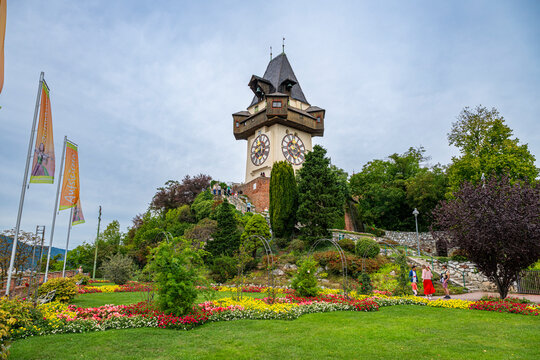 Castle Hill hosts Clock Tower with gardens and visitors in Graz during a cloudy day in Austria
