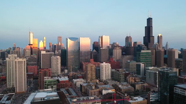 Chicago skyline at sunset with golden light hitting modern glass skyscrapers in downtown urban district.