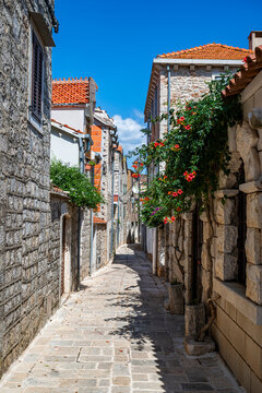 Explore narrow stone streets lined with flowers in the old city of Stari Grad, a historic site in Croatia