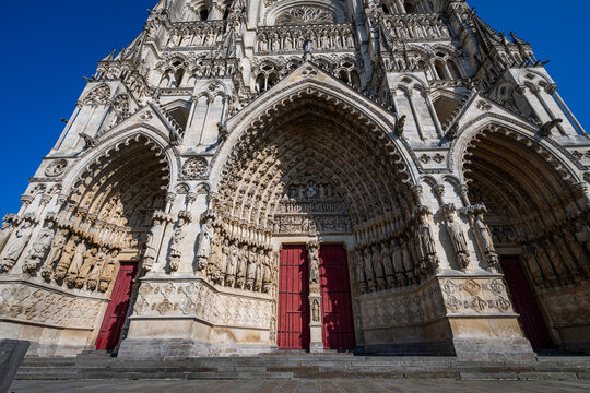 Cathedral of Amiens features detailed sculptures and archways under clear blue skies in France
