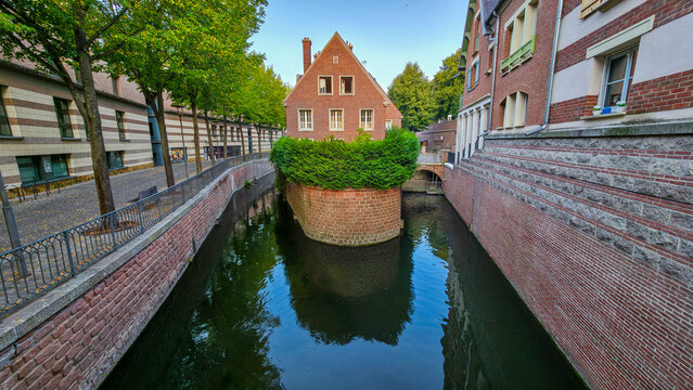 Small channel surrounded by buildings and green plants in Amiens offers a view of the waterway and architecture during the day