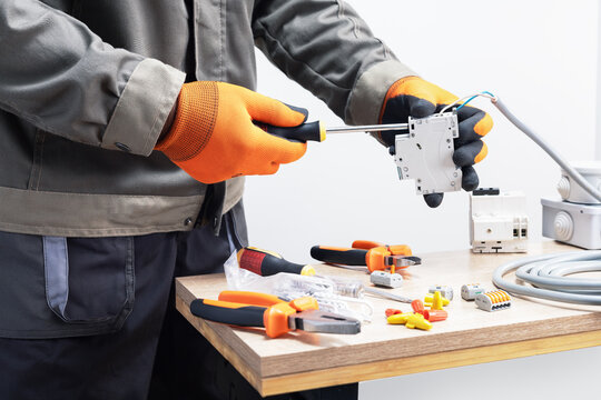 Electrician in gloves working with circuit breaker.
