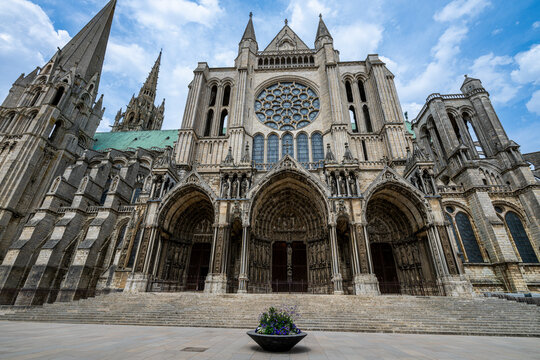 Detail of the facade and entrance of the Cathedral of Chartres in France with intricate designs and large stained glass windows