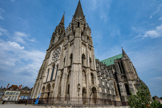 Cathedral of Chartres shows tall towers and intricate stonework under blue sky in France