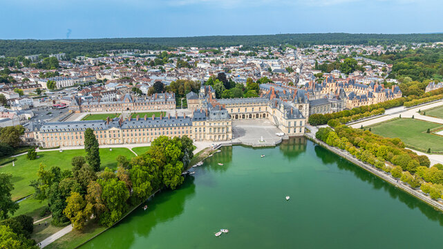 Explore Fontainebleau Palace from above, showcasing its gardens and architecture along the serene waters and surrounding area in France