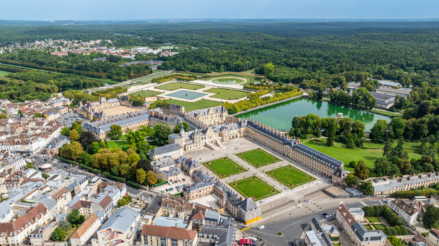 Aerial view shows Fontainebleau palace and surrounding gardens in France with greenery in the distance during daytime