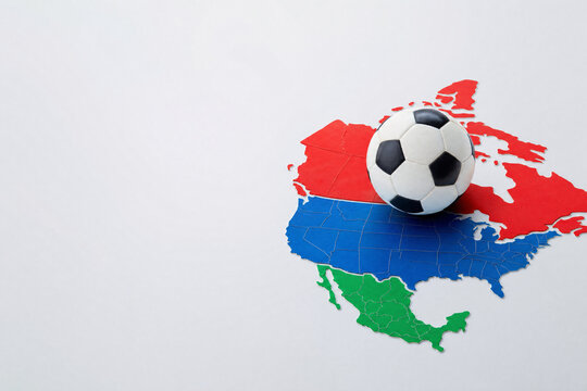 Soccer ball resting on a colorful map of North America including Canada, USA, and Mexico for the 2026 international football tournament and sporting events.