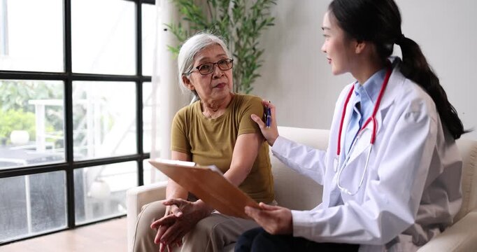 Asian doctor consulting senior woman, discussing medical information and providing emotional support during a routine check-up, focusing on patient care and well-being